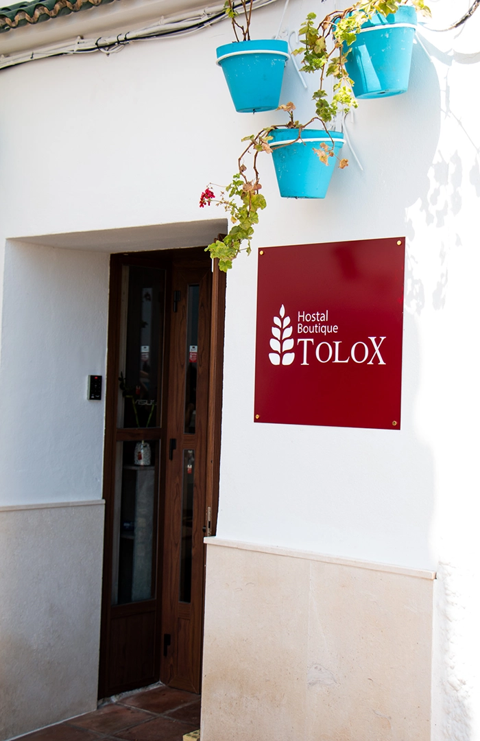 Fachada principal del Hostal Tolox Sierra de las Nieves, edificio andaluz tradicional rodeado de naturaleza en un entorno único.