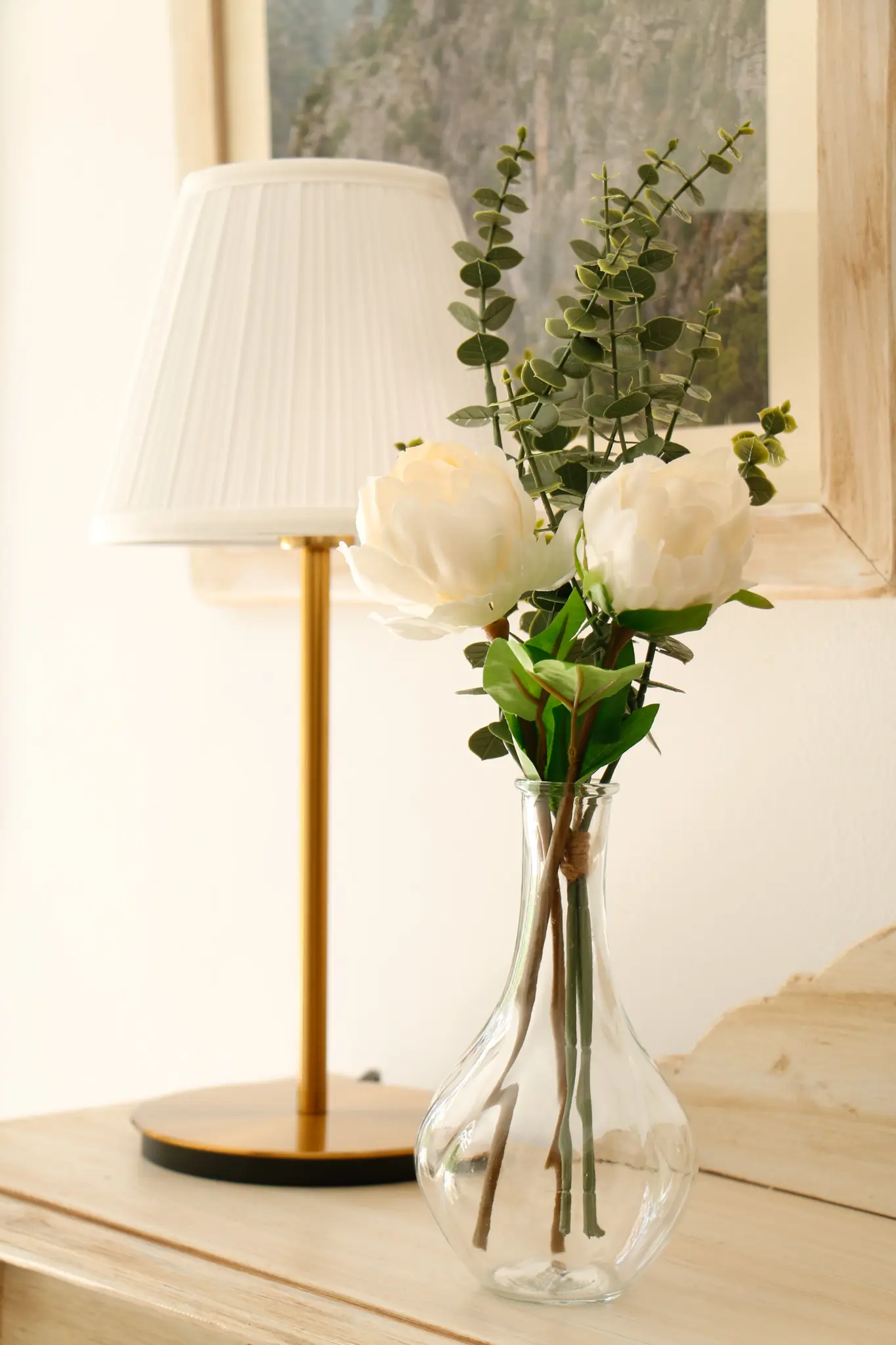 Lámpara de mesa y jarrón con flores decorando una zona común del Hostal Tolox, creando un ambiente acogedor en la Sierra de las Nieves