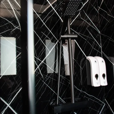 Imagen de la ducha en el baño de una habitación del Hostal Tolox, con mampara de cristal y diseño funcional para el confort del huésped