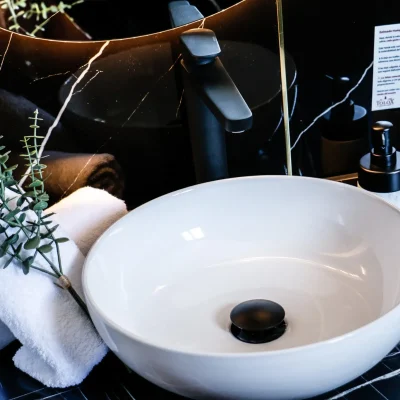 Lavabo del baño en una habitación del Hostal Tolox, con espejo y grifería moderna, ofreciendo un entorno cuidado y funcional para los huéspedes