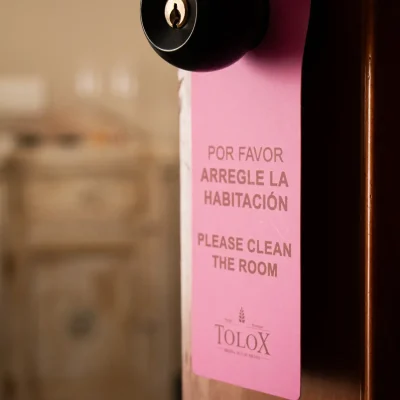 Cartel de 'arreglen la habitación' colgado en la puerta de una habitación del Hostal Tolox, indicando solicitud de servicio de limpieza
