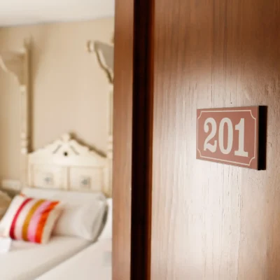 Puerta semiabierta de una habitación del Hostal Tolox con vista parcial de la cama al fondo, transmitiendo sensación de acogida y confort