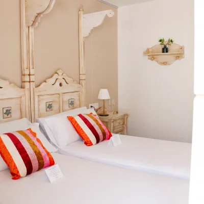 Dos camas individuales en una habitación del Hostal Tolox, ideales para compartir estancia en un entorno tranquilo de la Sierra de las Nieves