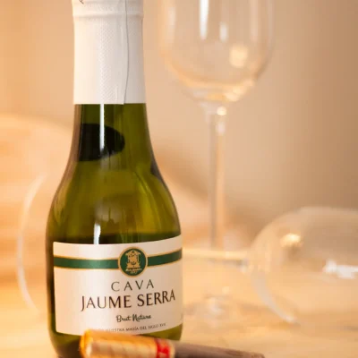 Botella de cava acompañada de dos copas de cristal y chocolates sobre una bandeja, como detalle especial en una habitación del Hostal Tolox en la Sierra de las Nieves