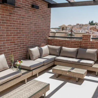 Espacio exterior del Hostal Tolox con sofá de exterior y decoración cuidada, ideal para relajarse al aire libre en la Sierra de las Nieves