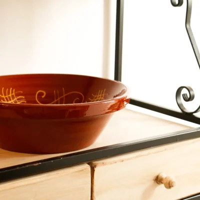 Plato de arcilla decorativo colocado sobre una estantería en una zona común del Hostal Tolox, reflejando el estilo tradicional andaluz