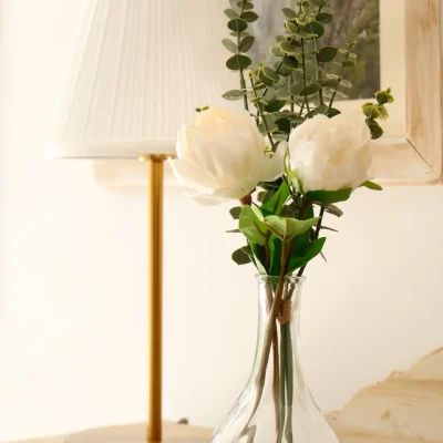 Detalle de zona común en el Hostal Tolox con lámpara de mesa, jarrón con flores y mobiliario acogedor, en un ambiente tranquilo de la Sierra de las Nieves