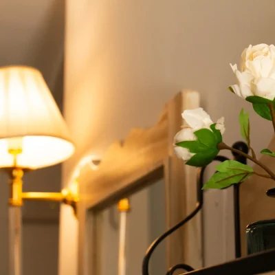Lámpara de mesa junto a un jarrón con flores en una habitación del Hostal Tolox, creando un ambiente acogedor y cuidado en la Sierra de las Nieves